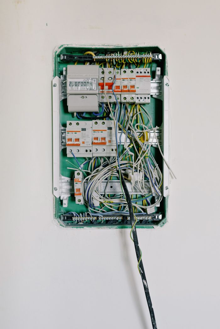 Services Switchboard with wires connected to electrical switches with circuit breakers installed on white wall